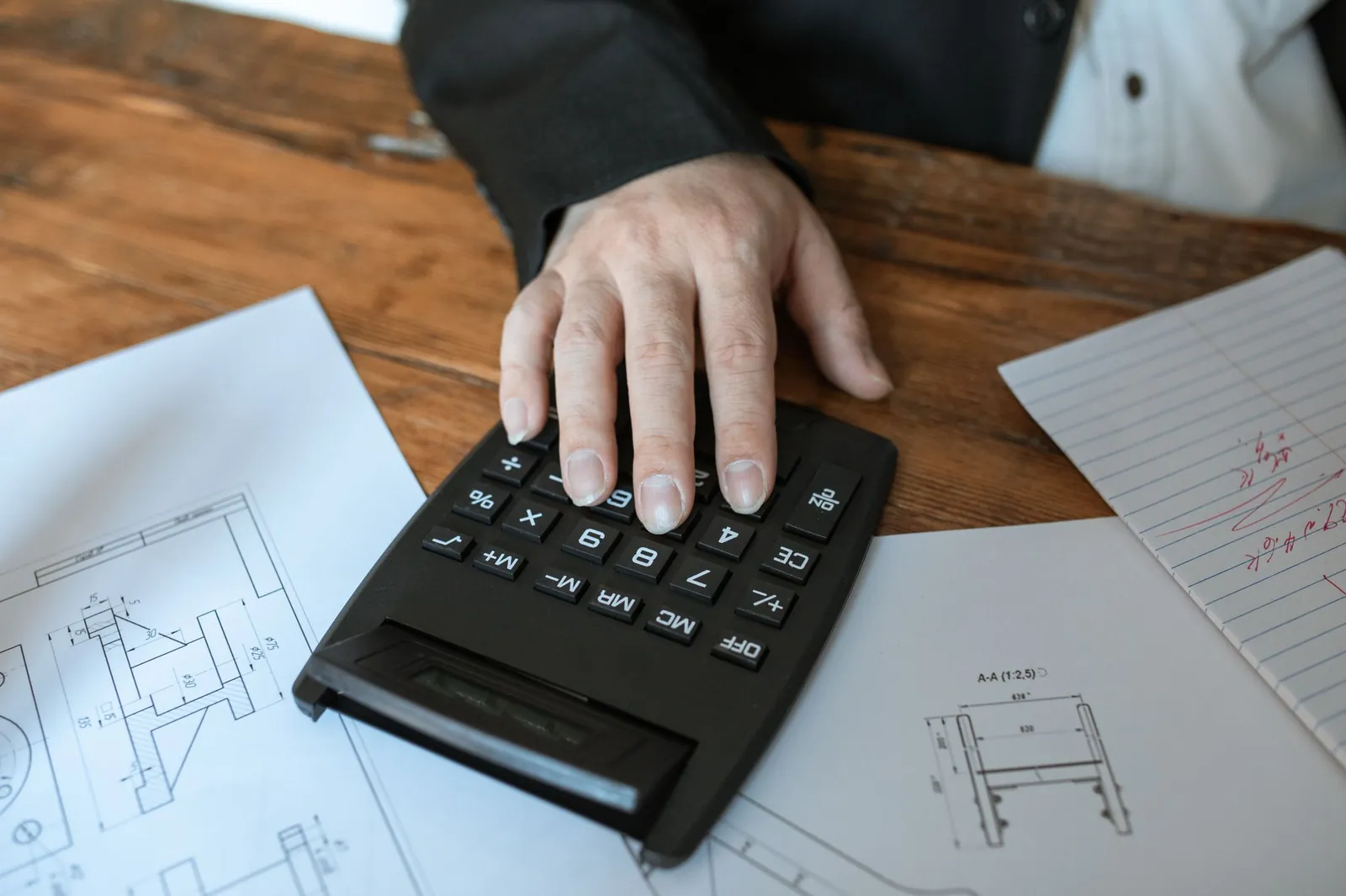 Hand op een rekenmachine naast een plattegrond